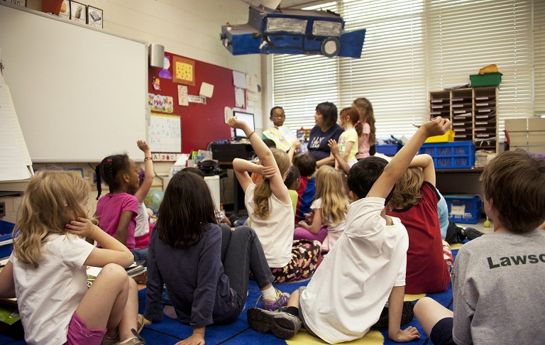 Kinder sitzen auf einem Teppich in einem Klassenzimmer
